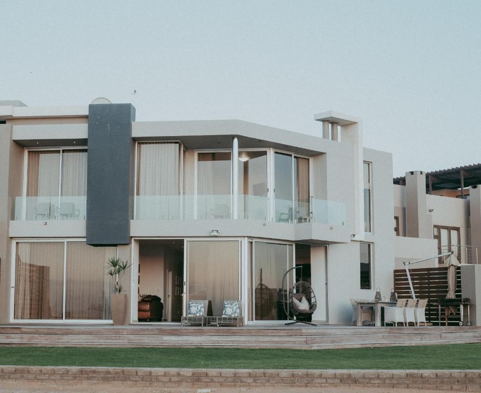 ein großes weißes Haus mit Glasfenstern und einem Tisch in der Unterkunft Oceana View in Swakopmund