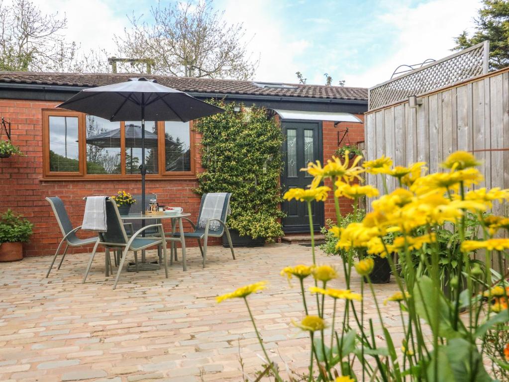 a patio with a table and chairs and an umbrella at Kilmory Lodge in Poulton le Fylde