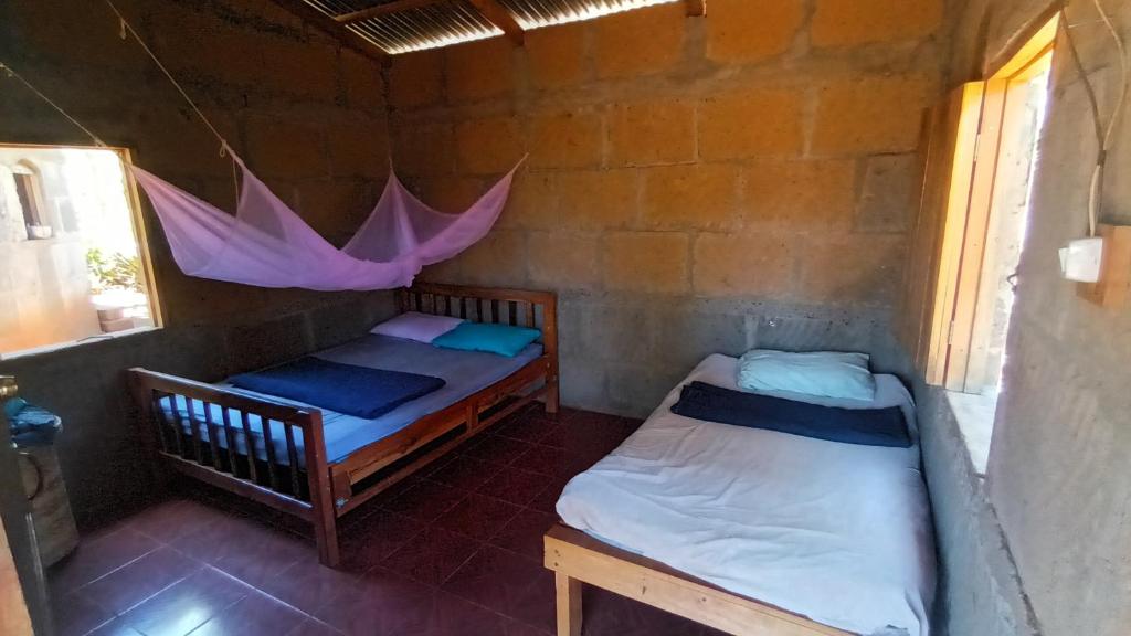 2 Betten in einem Zimmer mit einem rosa Regenschirm in der Unterkunft Finca Joco Mico in Diriamba