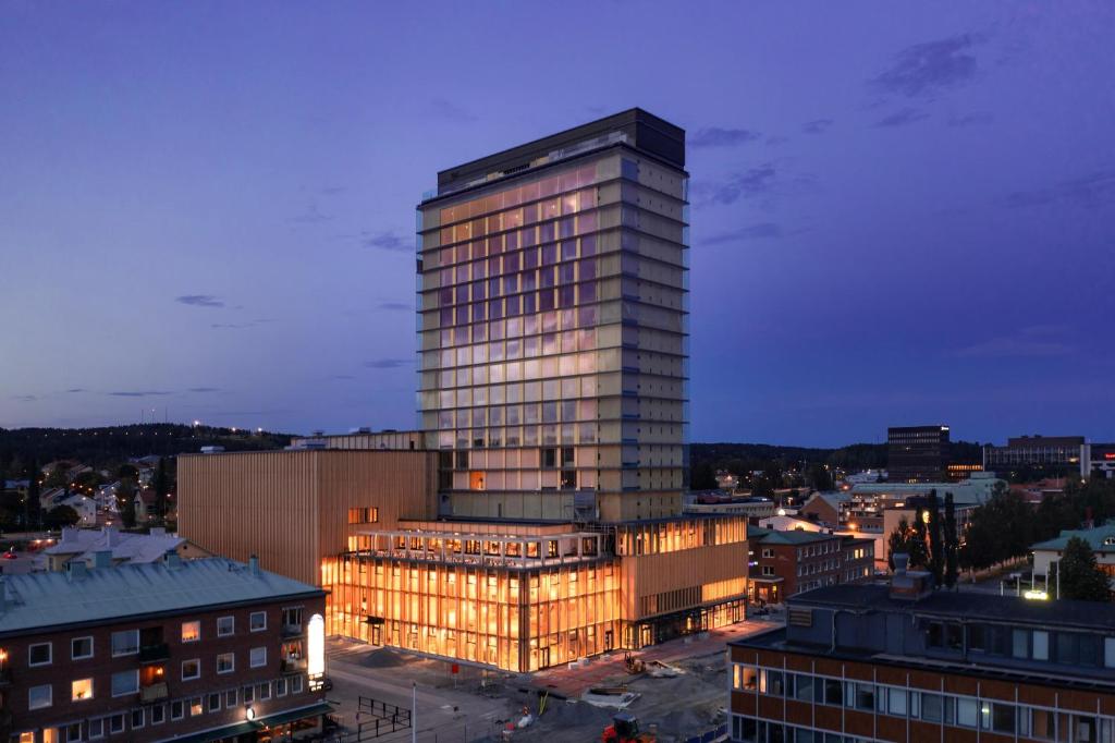 a tall glass building in a city at night at The Wood Hotel by Elite, Spa & Resort in Skellefteå