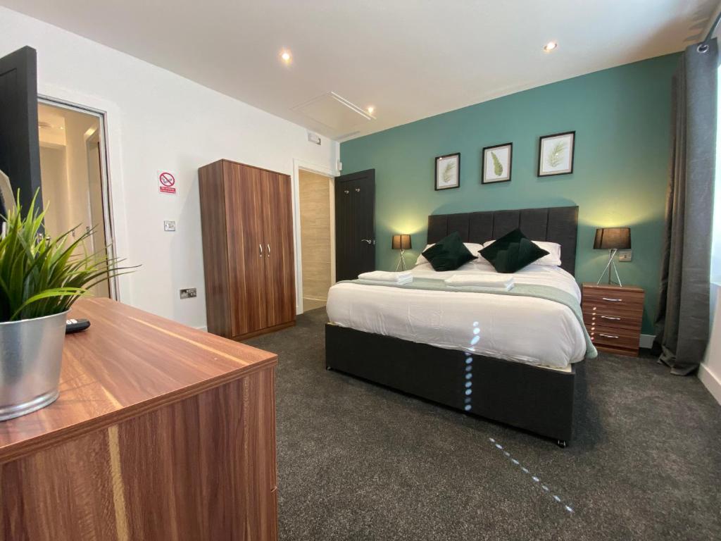 a bedroom with a large bed and a wooden dresser at Modern 3 bedroom apartment close to the city centre in Liverpool