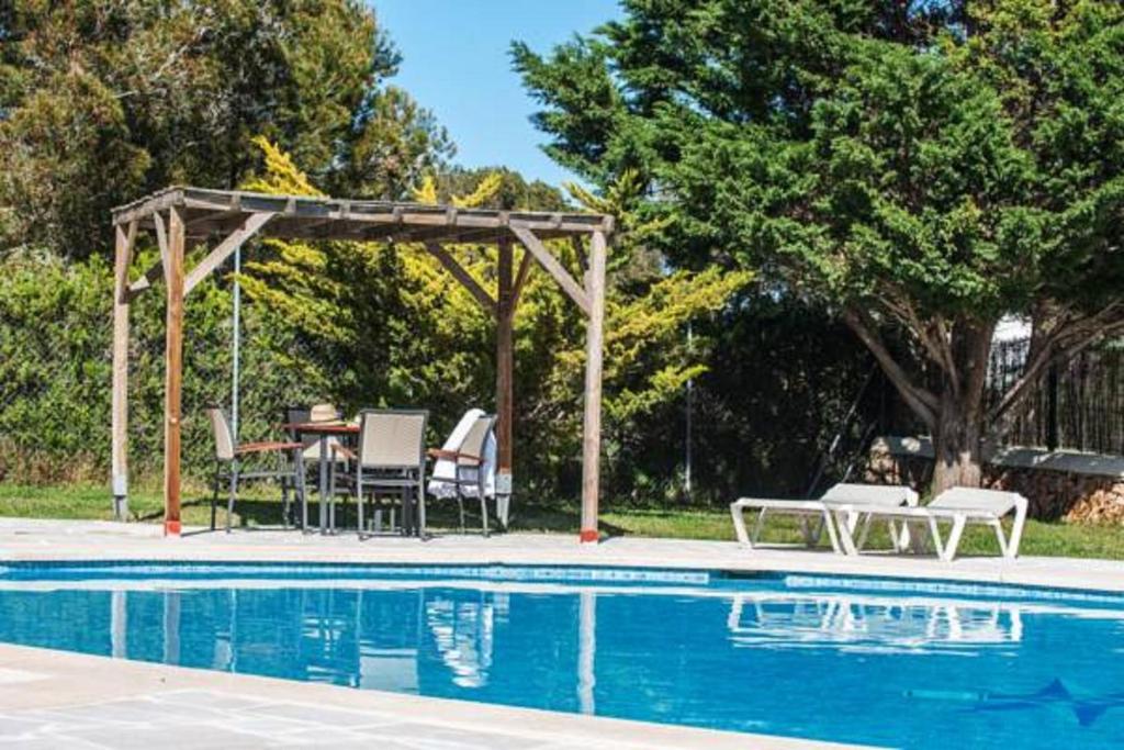 een patio met een tafel en stoelen naast een zwembad bij Serena Sol in Cala Serena