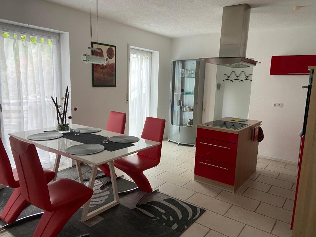 a kitchen with a dining room table and red chairs at Kraichgauer - Cent in Reichartshausen
