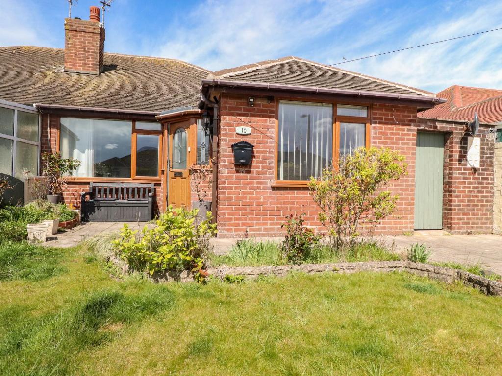a brick house with a porch and a yard at Bungalow by the Sea in Cleveleys