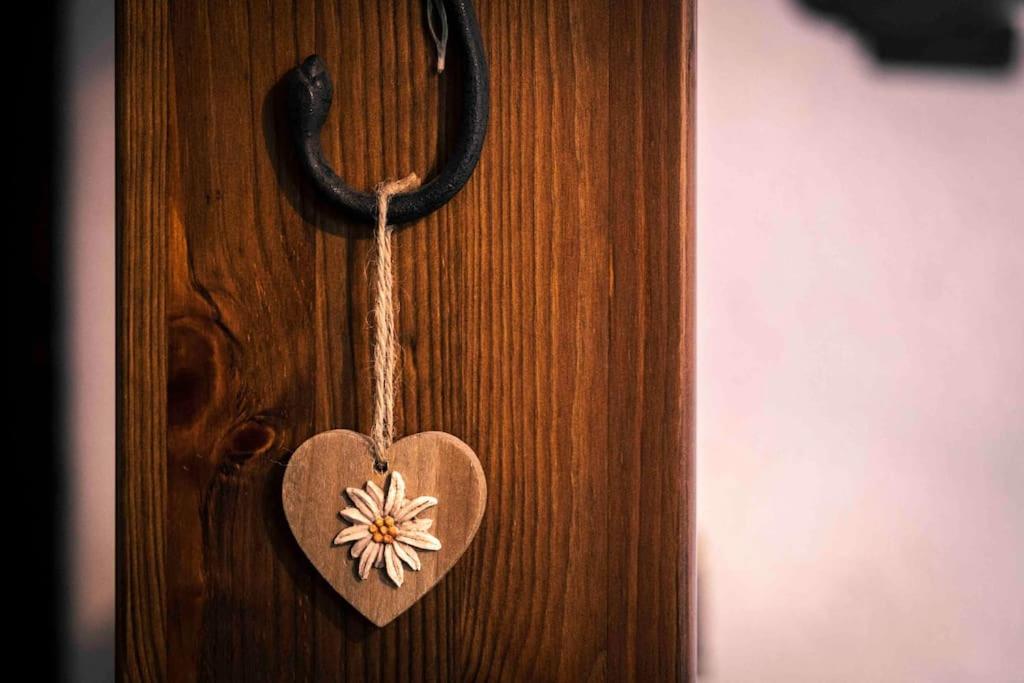 een houten hart met een bloem op een houten deur bij Caldo appartamento vicino a Bormio + wifi + garage in Santa Caterina Valfurva