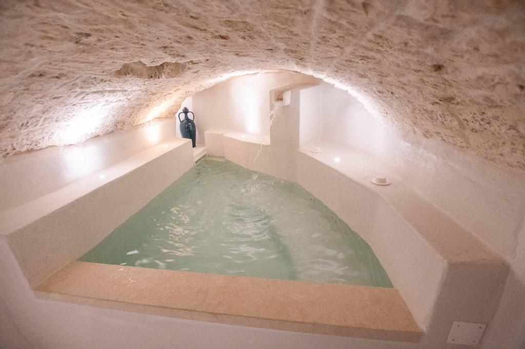 une baignoire dans une grotte avec de l'eau dedans dans l'établissement Suite Oronzo By PREGIO VILLAS, à Ostuni