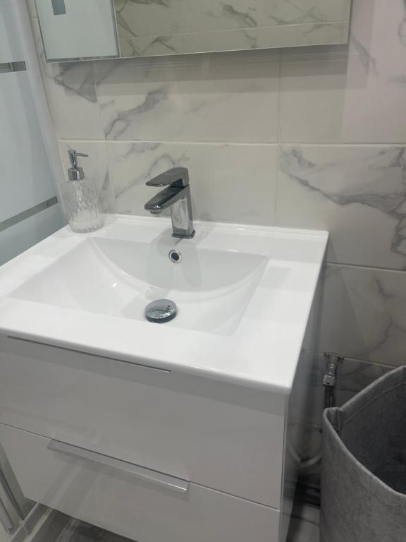 lavabo blanco con grifo y espejo en Charming parisian apartment, en París