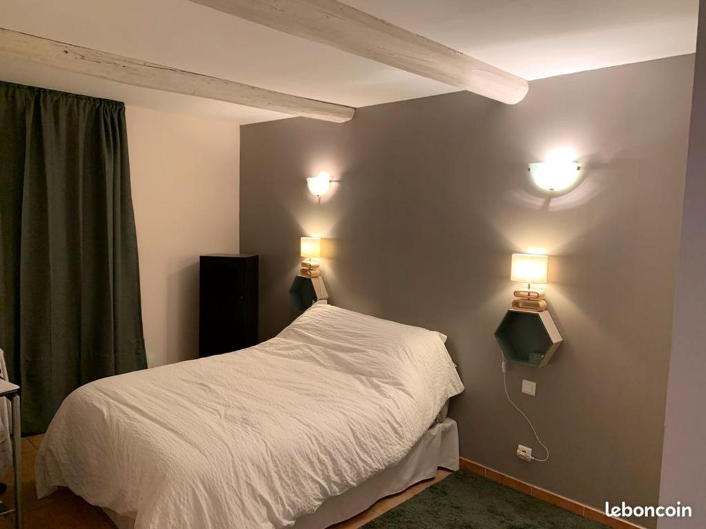 sypialnia z łóżkiem i 2 lampkami na ścianie w obiekcie Villa Nans w mieście Paradou