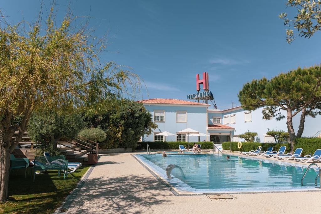 einen Pool mit Liegestühlen und ein Gebäude in der Unterkunft Hotel Neptuno in Peniche