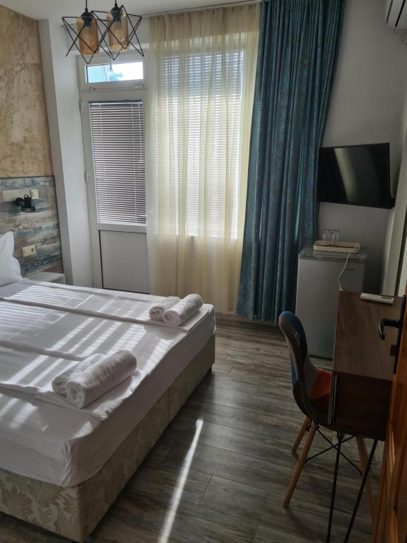 um quarto com uma cama, uma secretária e uma televisão em Къща за гости СТЕЛА em Primorsko