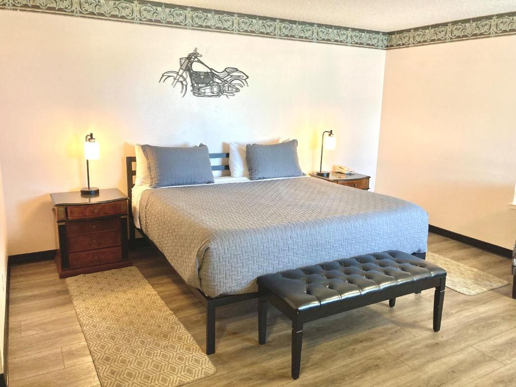 Un dormitorio con una cama con un banco al lado en Coast Riders Inn, en San Simeon