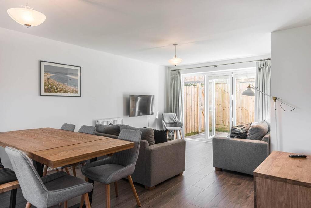 a living room with a table and chairs and a couch at Beach Mews - Modern townhouse with patio and private parking in Kent