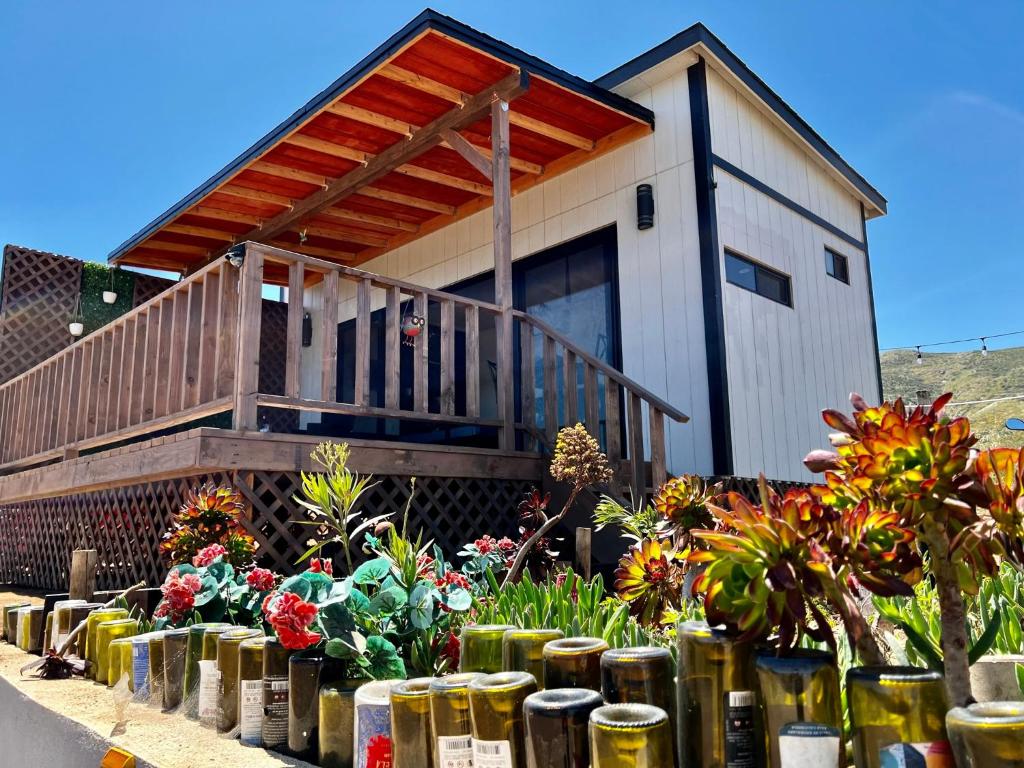 una casa con una terraza y flores delante de ella en Colibrí Tiny House en Valle de Guadalupe