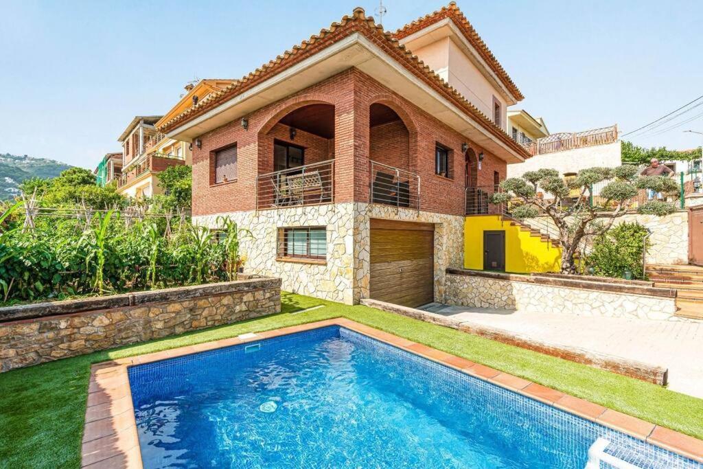 a house with a swimming pool in front of a house at Casa rustica con piscina y jardin in Pineda de Mar