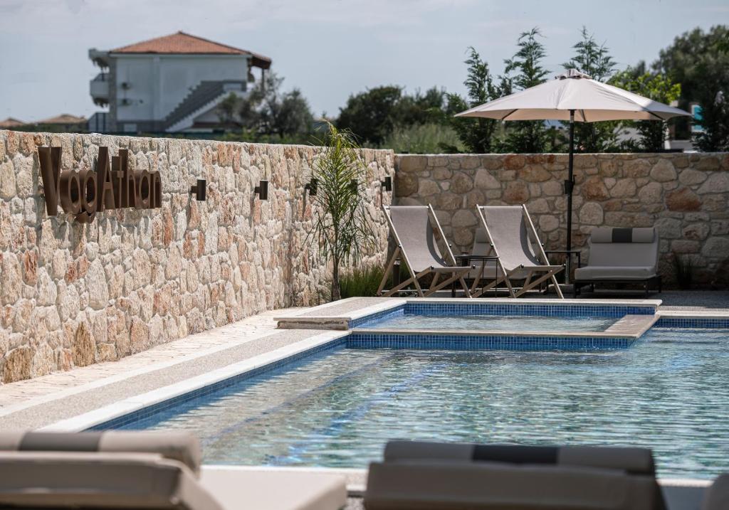 a swimming pool with two chairs and an umbrella at VagAthan - Lux Holidays in Afitos