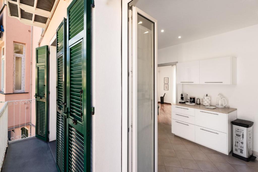 a kitchen with white cabinets and green shutters at Casa mia a Nervi in Genoa