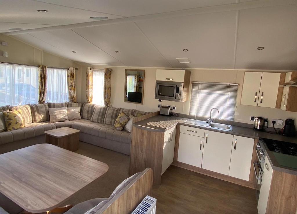 a kitchen and living room with a couch and a table at Beach Caravan Holiday Home in Mablethorpe
