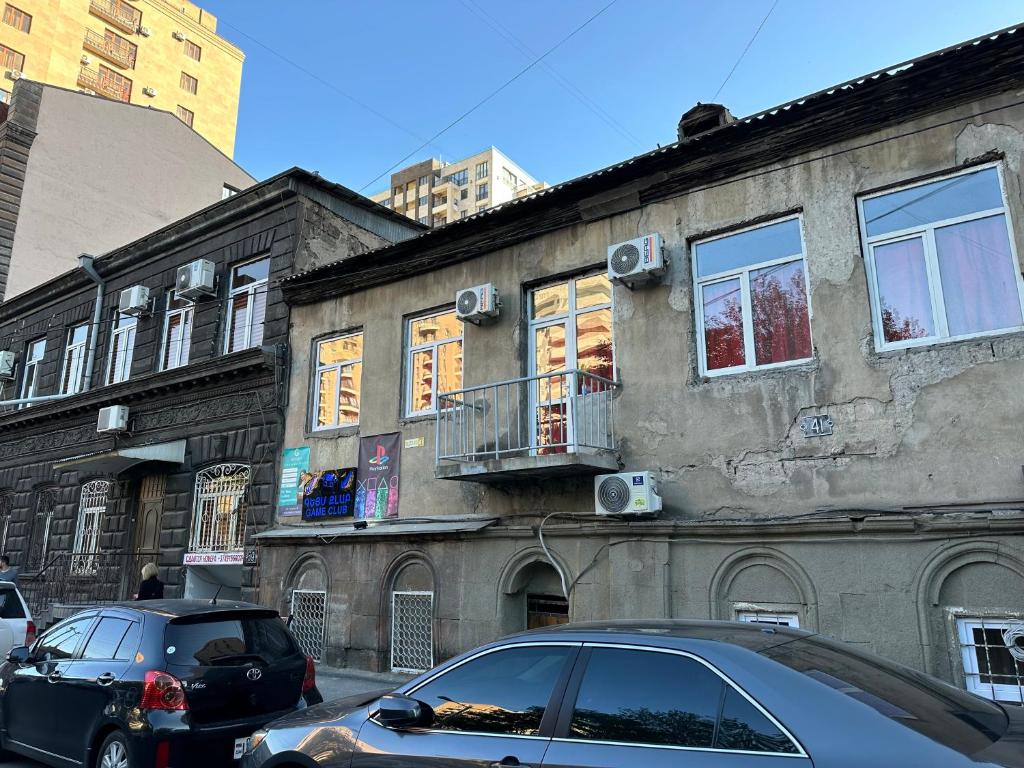 un vieux bâtiment avec des voitures garées devant lui dans l'établissement Apartments on Buzand street, à Erevan