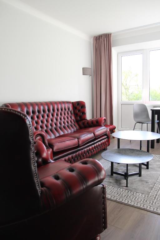 a living room with a leather couch and a table at Luxuria Modern Apartments - Self Check-in in Šiauliai