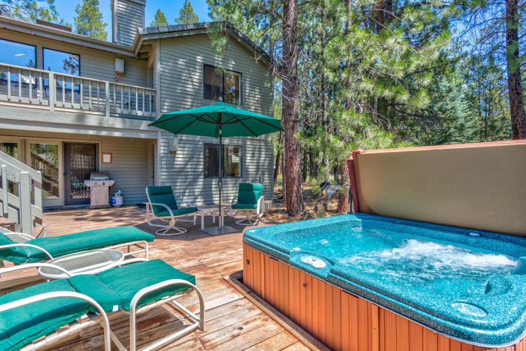 a hot tub on a deck with chairs and an umbrella at Shadow - Unit 1 in Sunriver