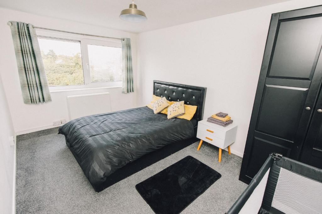 a bedroom with a black bed and a window at Luxe Spacious & Central 2Bed Luton Apartment - Free Parking - Free Wi-Fi - Near LTN Airport & L&D Hospital in Luton