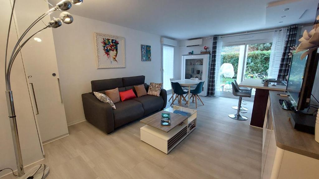 un salon avec un canapé et une table dans l'établissement Charmant Appartement résidentiel avec Terrasse, Jardin Privatif et Piscine à Cannes, à Cannes