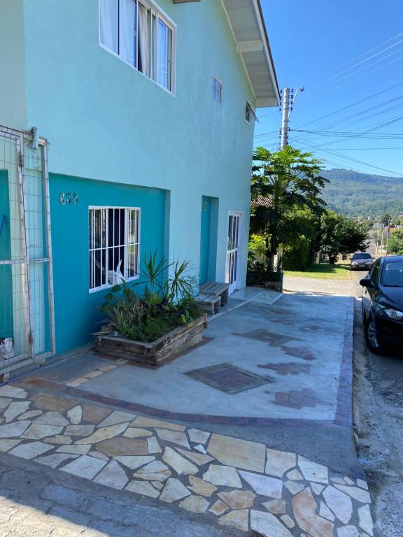 un edificio azul con un coche aparcado delante de él en Casa da Vila Pousada en Três Coroas