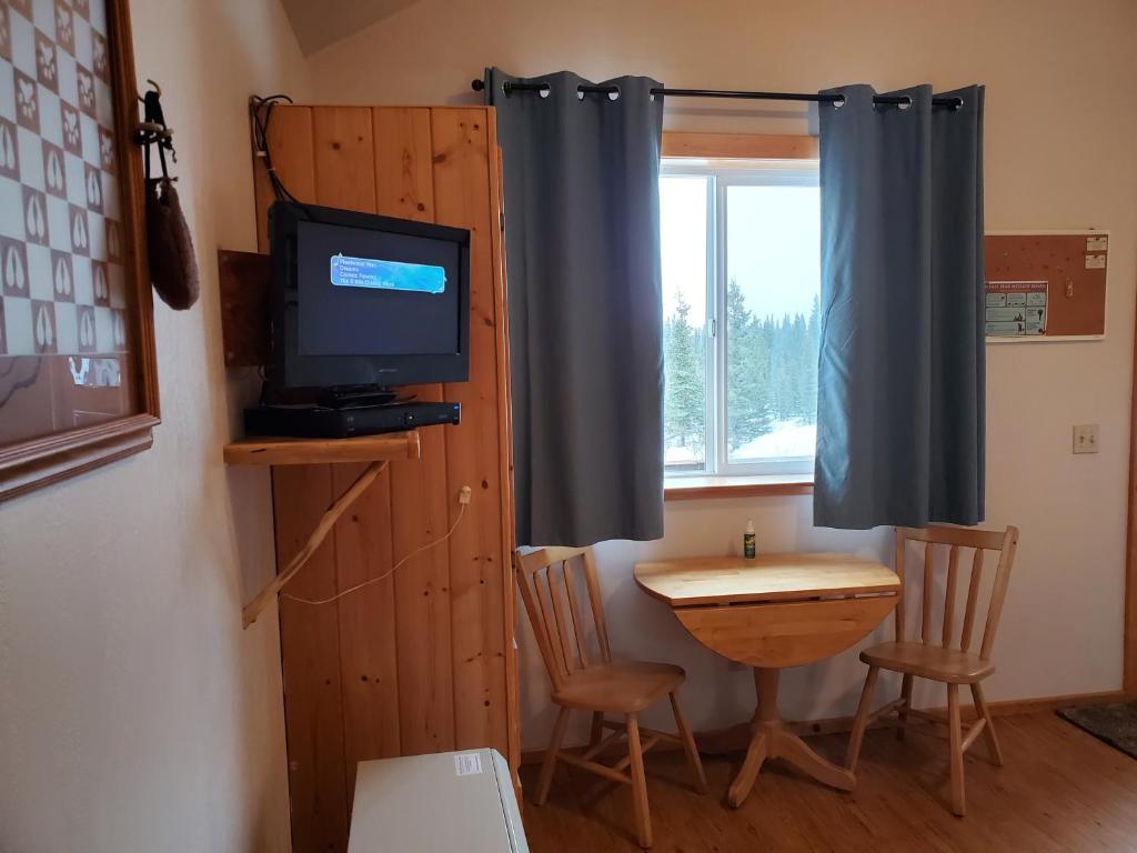 Habitación con mesa, TV, mesa y sillas. en Alaskan Spruce Cabins, en Healy