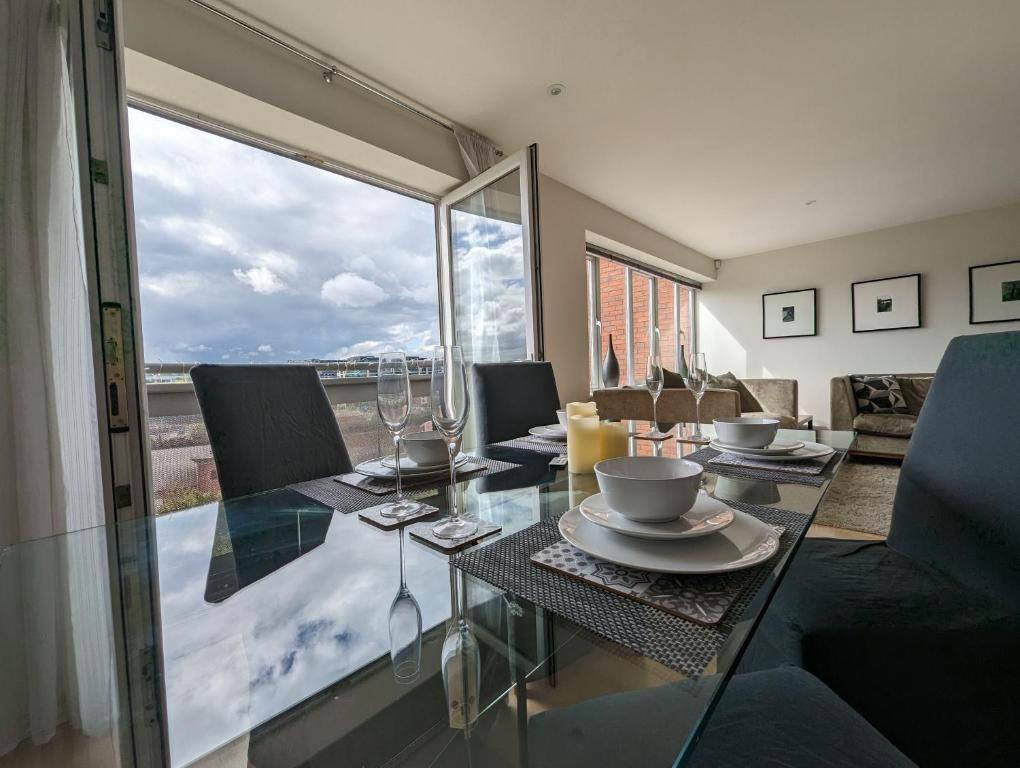 een eetkamer met een glazen tafel en stoelen bij Quayside apartment with riverside views & parking in Newcastle upon Tyne