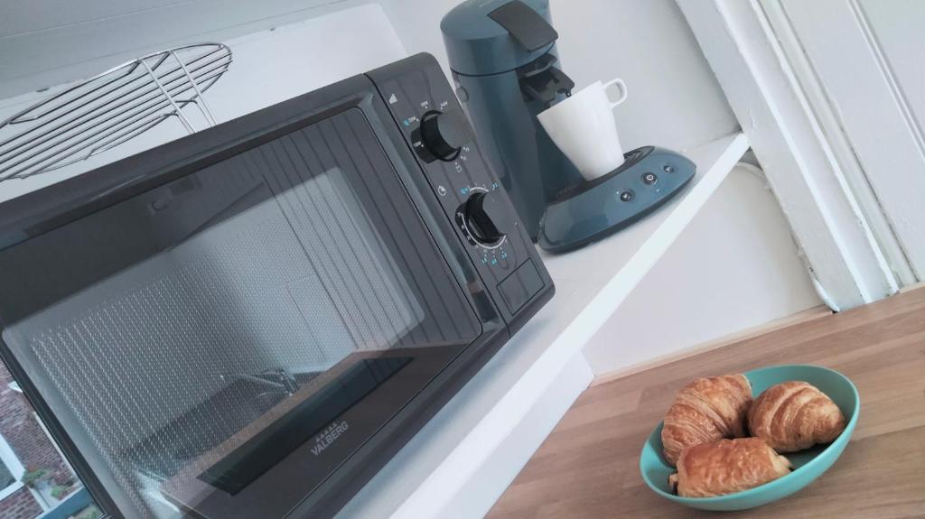 a microwave with a bowl of bread and a bowl of croissants at Le Chalet in Mers-les-Bains