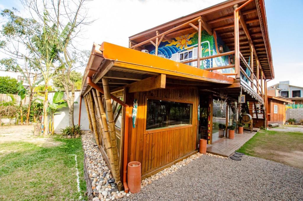 uma casa com uma fachada de madeira com um edifício em Hostel Quintal do Rosa na Praia do Rosa