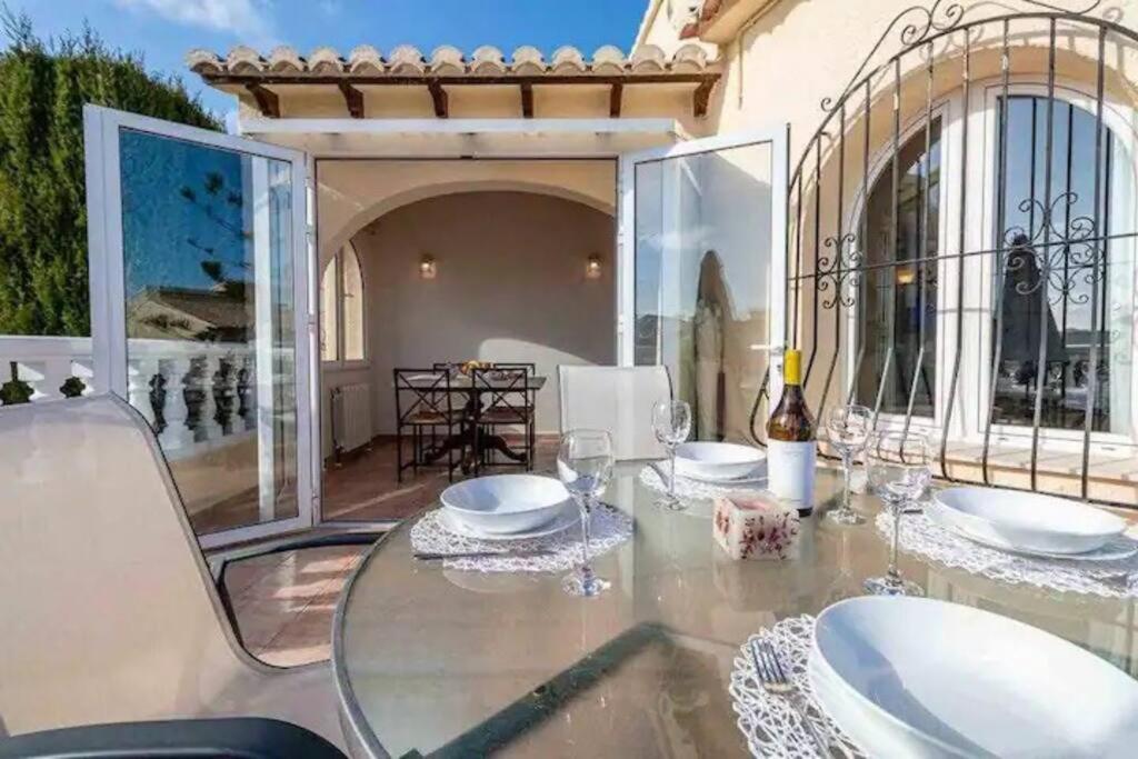 a dining room with a glass table on a patio at Beautiful Villa Close to Xabia & Moraira in Benitachell