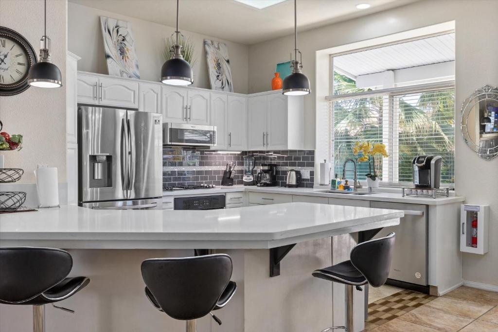 a kitchen with white cabinets and a large island with chairs at KMEL HOME in Bakersfield
