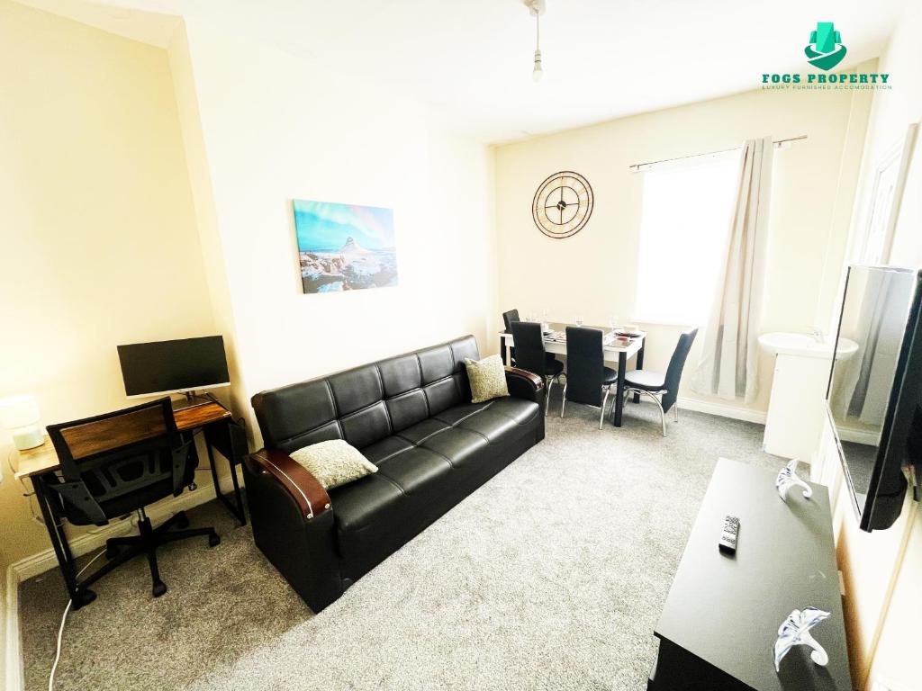 a living room with a black leather couch and a table at Fogs Property - Darlington City Apartments in Darlington