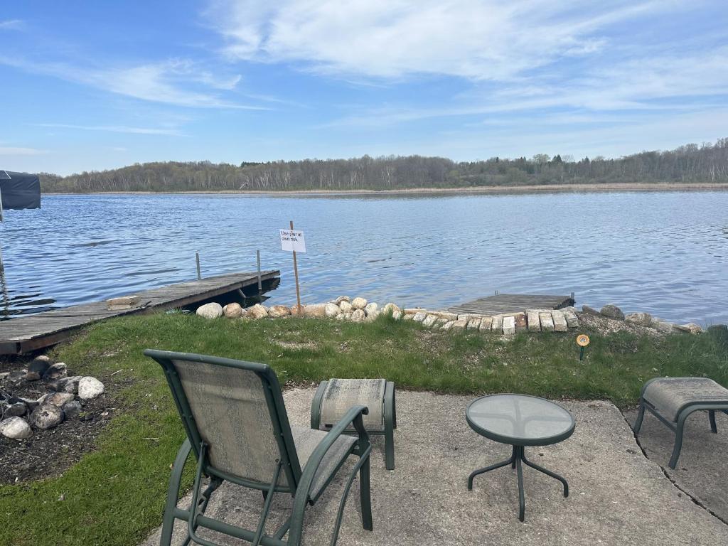 a group of chairs and a table next to a lake at Fun Lake House on Long Lake near beaches home in Campbellsport