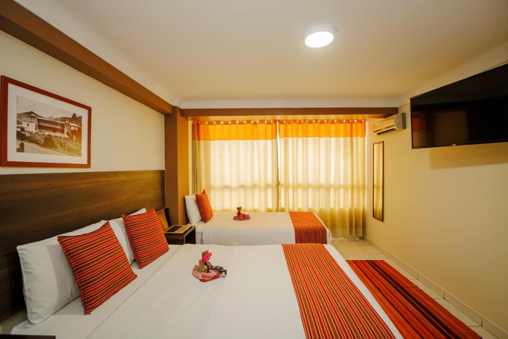 um quarto de hotel com duas camas e uma televisão em Principe III em Cusco