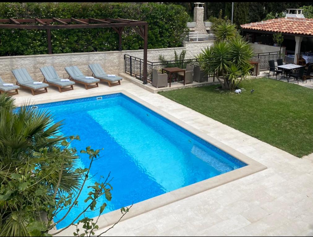 een zwembad in een achtertuin met stoelen en een tafel bij Villa Mediterranea in Bol