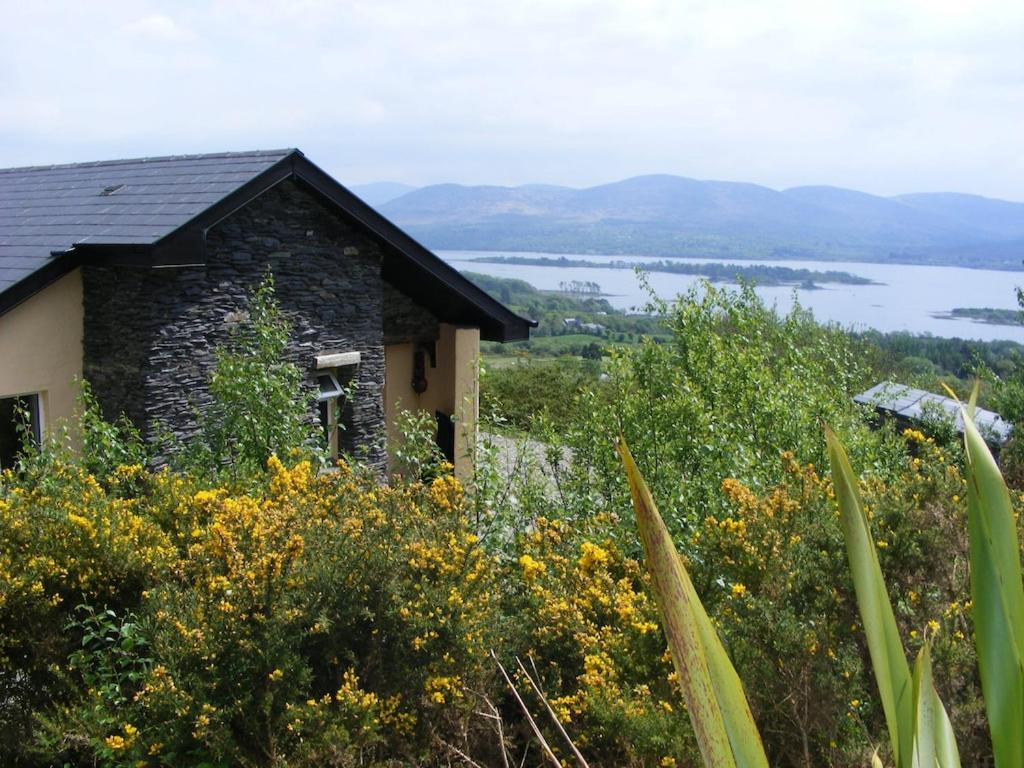 肯梅爾的住宿－Charming Two Bedroom Cottage with Magnificent Sea Views. 10 minutes from Kenmare，一座石头房子,位于一座小山上,享有湖景