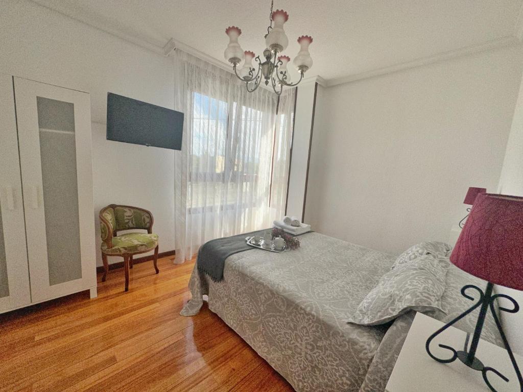 a bedroom with a bed and a chair and a window at A Estribor - 20001 in Argoños