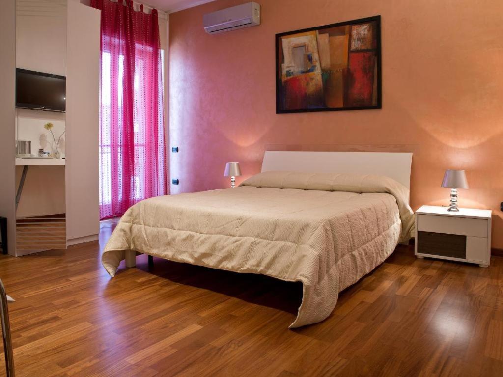 サレルノにあるB&B スル コルソのピンクの壁とウッドフロアのベッドルーム1室(大型ベッド1台付)