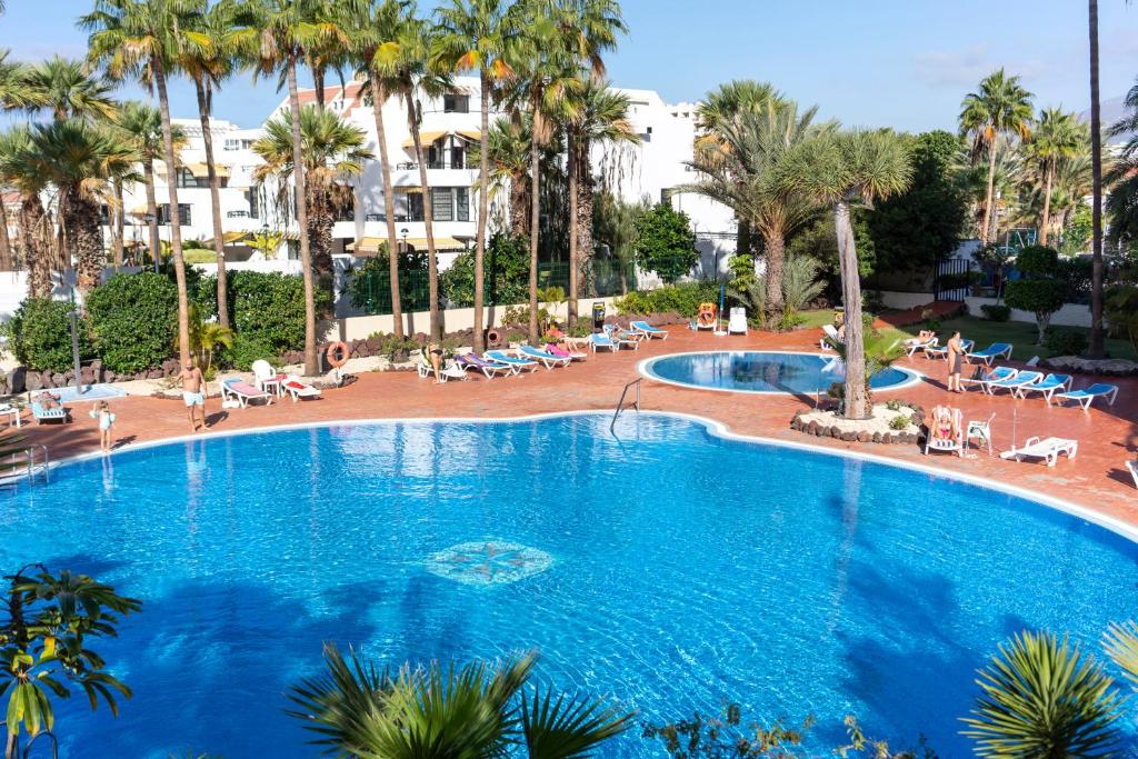 una gran piscina con palmeras y un edificio en El Dorado 114 luxury with full air-conditioning, en Playa de las Américas