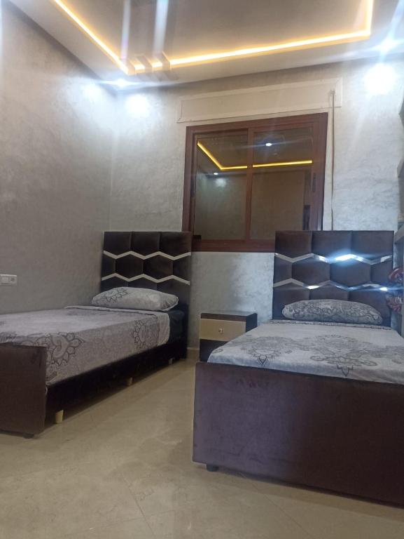 a bedroom with two beds and a mirror at Bel appartement in Chefchaouene