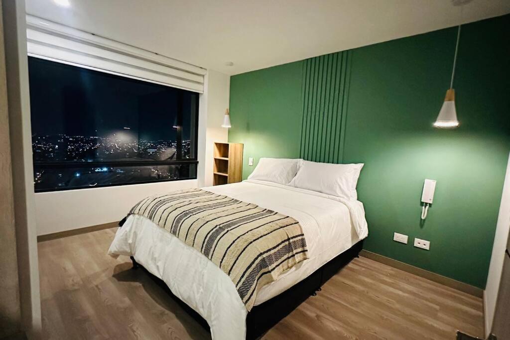 ein grünes Schlafzimmer mit einem Bett und einem Fenster in der Unterkunft Brand new Apt, perfect City view in Bogotá