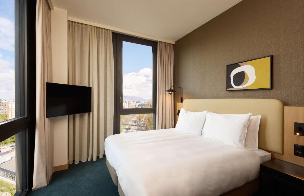 a hotel room with a bed and a large window at Adina Apartment Hotel Geneva in Geneva