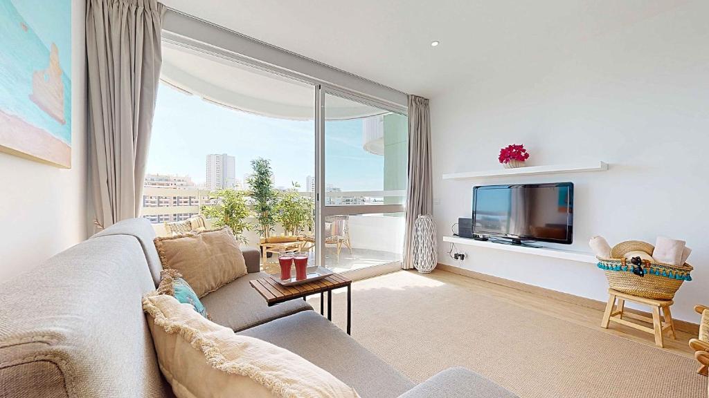 a living room with a couch and a large window at Apartamento da Avó Té - em frente à Praia c piscina in Portimão
