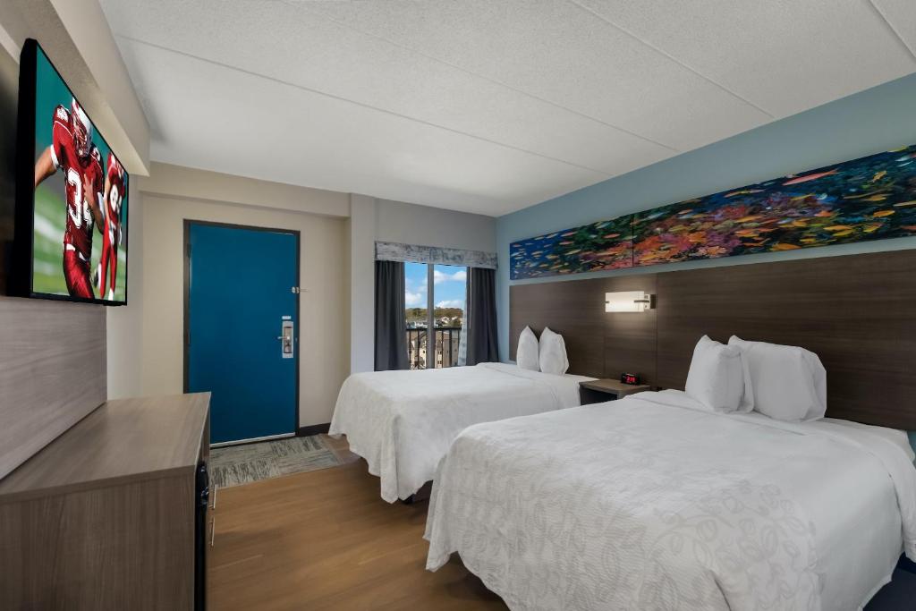 バージニアビーチにあるRed Roof PLUS & Suites Virginia Beach - Seasideのベッド2台が備わる客室で、壁には絵画が飾られています。