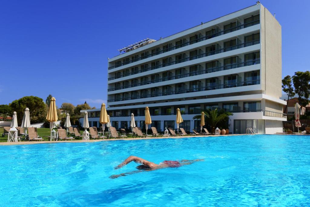 a person swimming in a pool in front of a hotel at Airotel Achaia Beach in Patra