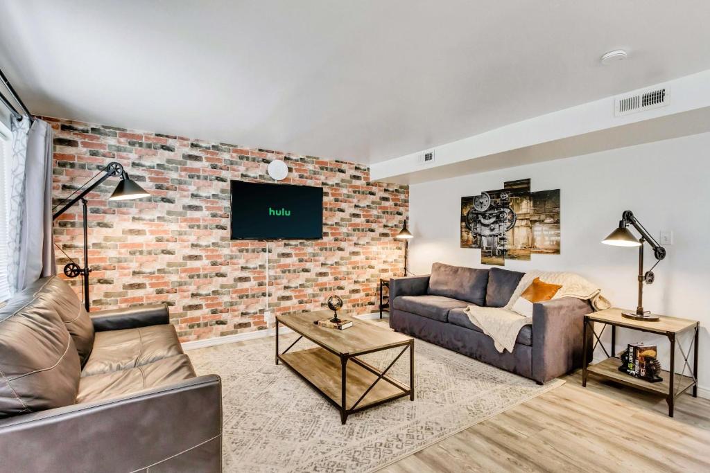 uma sala de estar com um sofá e uma parede de tijolos em Convenient - Near Hospitals - King Bed em Salt Lake City