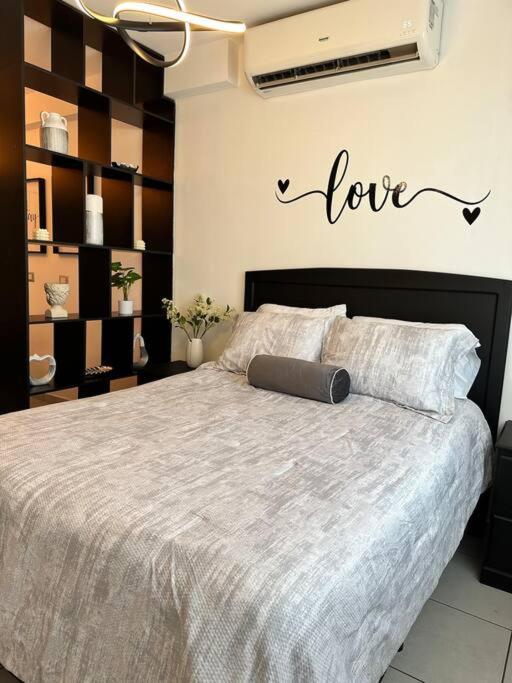 1 dormitorio con 1 cama con una señal de amor en la pared en Monoambiente Apart-Studio, en Tegucigalpa