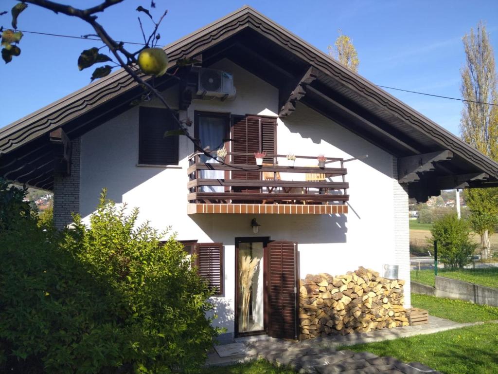 een wit huis met een balkon met een stapel houtblokken bij Holiday house with a parking space Tuheljske Toplice, Zagorje - 21224 in Dubrovčan